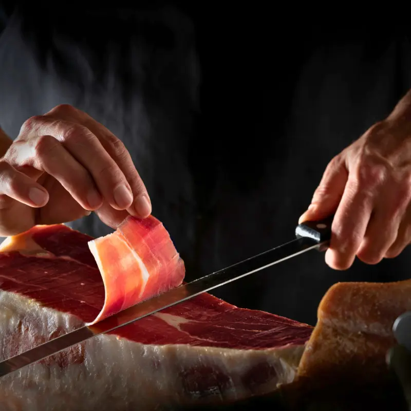 Le chef qui découpe un jambon devant des clients