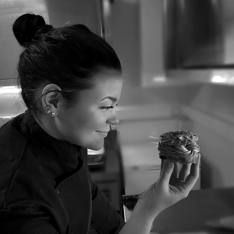 Maïlys, photo noire et blanc, tenant un paris-brest dans sa main